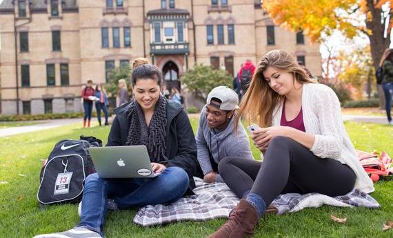 Three 뿪¼ students sitting on a blanket on the grass outside Old Main